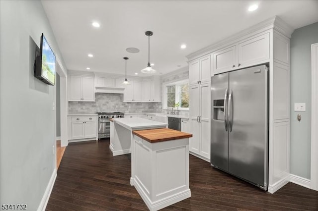 kitchen with stainless steel appliances, wood counters, a center island, white cabinets, and decorative backsplash