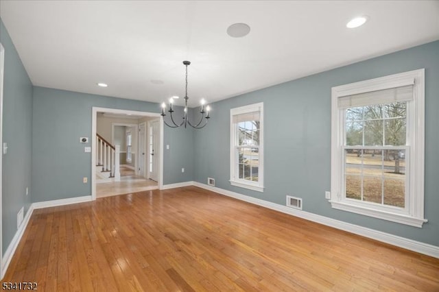 unfurnished dining area featuring light wood-type flooring, baseboards, stairs, and visible vents