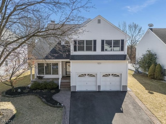 view of front of home with a garage, driveway, roof with shingles, a front lawn, and a chimney