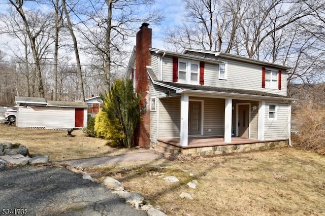 view of front of property featuring an outbuilding, covered porch, and a chimney