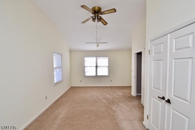 empty room with high vaulted ceiling, baseboards, a ceiling fan, and light colored carpet