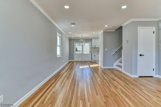 empty room featuring light wood-type flooring, baseboards, stairs, and visible vents