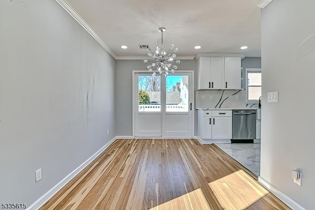 unfurnished dining area with a notable chandelier, visible vents, ornamental molding, light wood-type flooring, and baseboards