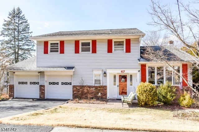 view of front of house with driveway, an attached garage, and brick siding