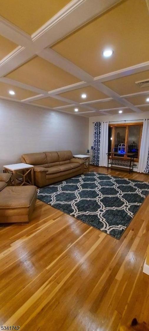 unfurnished living room featuring visible vents, coffered ceiling, wood finished floors, and recessed lighting