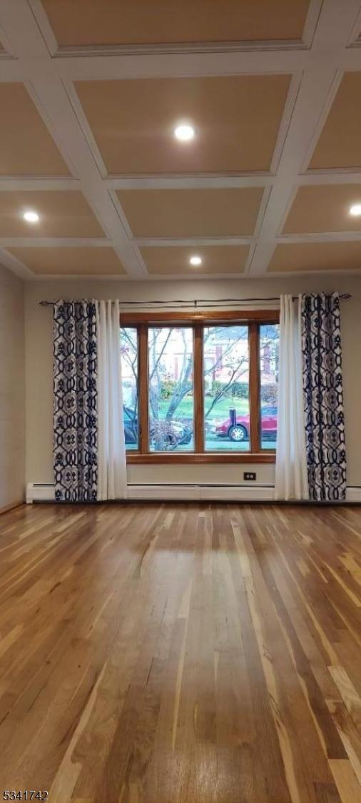 spare room featuring a baseboard radiator, coffered ceiling, baseboard heating, and wood finished floors