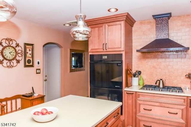 kitchen featuring arched walkways, dobule oven black, stainless steel gas cooktop, wall chimney range hood, and backsplash