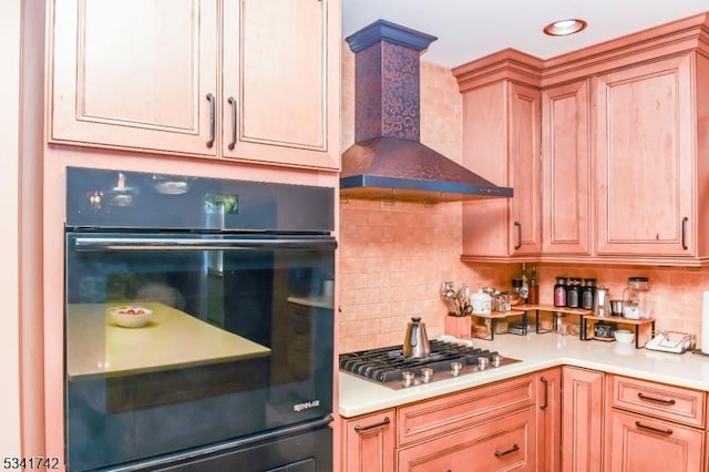 kitchen with dobule oven black, wall chimney exhaust hood, stainless steel gas cooktop, and tasteful backsplash