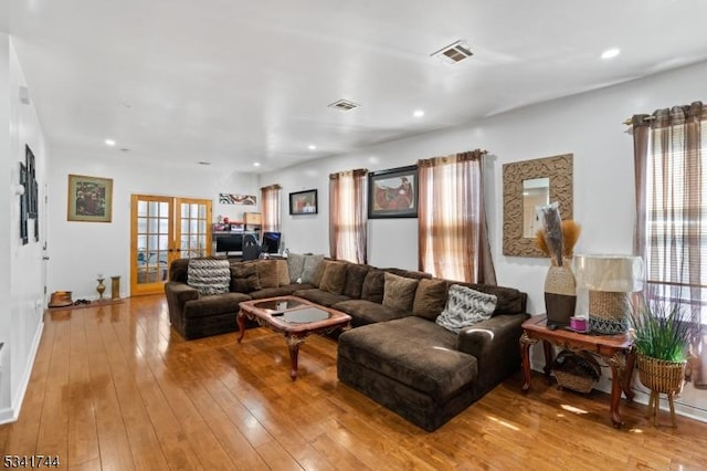 living room featuring hardwood / wood-style flooring, recessed lighting, french doors, and visible vents