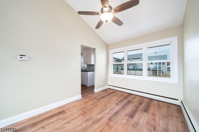 unfurnished room featuring baseboards, vaulted ceiling, light wood finished floors, and baseboard heating