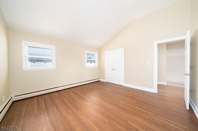 empty room with vaulted ceiling, a baseboard radiator, wood finished floors, and baseboards