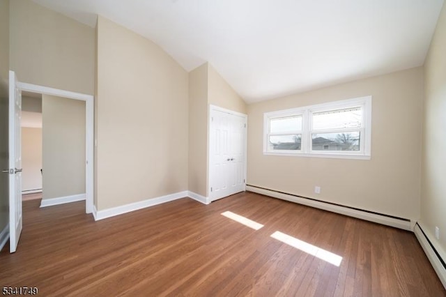 unfurnished room featuring a baseboard radiator, a baseboard heating unit, wood finished floors, baseboards, and vaulted ceiling