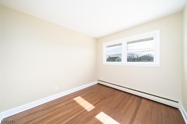 spare room featuring baseboards, baseboard heating, and wood finished floors