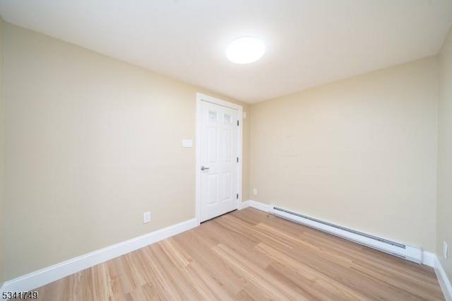 spare room with light wood finished floors, baseboards, and a baseboard heating unit