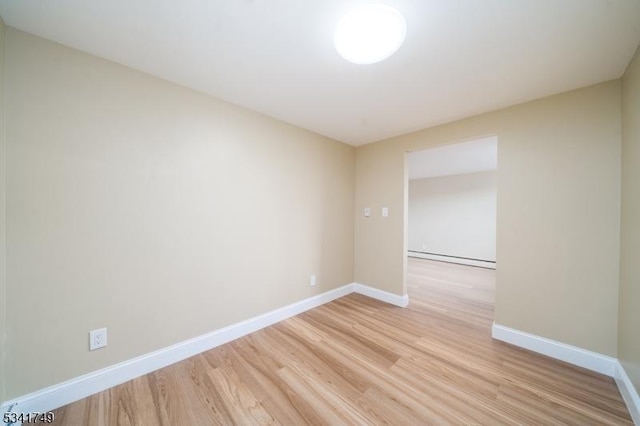 unfurnished room featuring light wood finished floors, a baseboard radiator, and baseboards