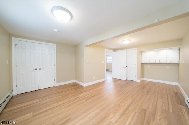 spare room featuring baseboards, baseboard heating, a baseboard radiator, and light wood-style floors