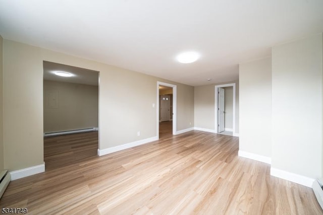 empty room featuring a baseboard radiator, baseboards, and light wood-style flooring