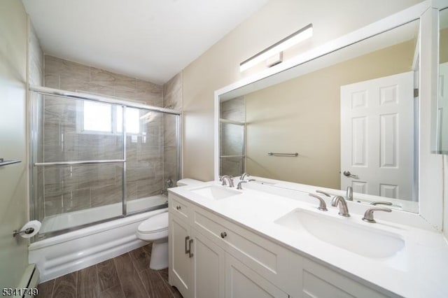 full bath featuring toilet, a baseboard radiator, a sink, and wood finished floors