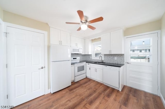 kitchen with white appliances, dark countertops, white cabinetry, and tasteful backsplash