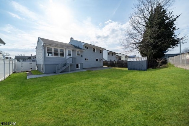 rear view of property with a fenced backyard, an outdoor structure, a lawn, and a storage unit