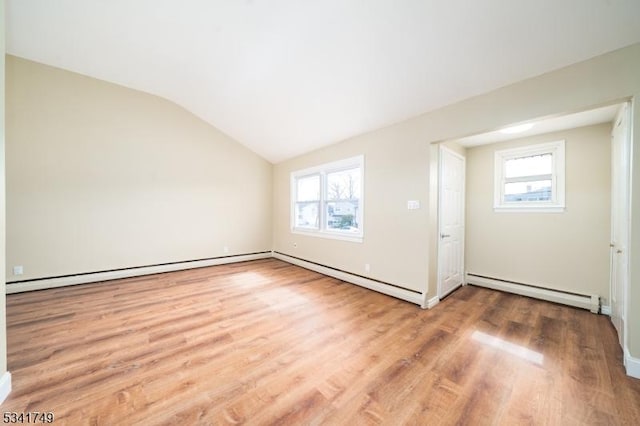 empty room with a healthy amount of sunlight, a baseboard radiator, wood finished floors, and lofted ceiling