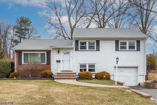 tri-level home featuring an attached garage, brick siding, a shingled roof, and a front yard