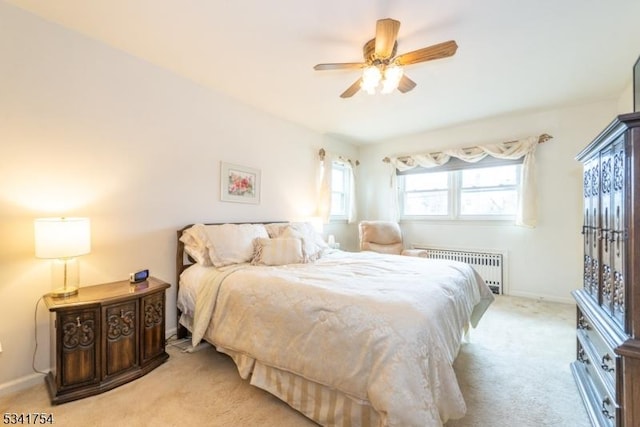 bedroom featuring light carpet, radiator heating unit, baseboards, and a ceiling fan