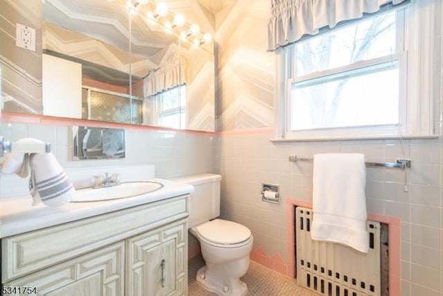 bathroom featuring tile walls, radiator, vanity, and toilet