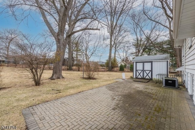 view of patio with a shed, fence, central AC, and an outdoor structure