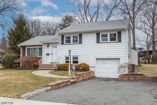 split level home featuring aphalt driveway, a front lawn, an attached garage, and a shingled roof