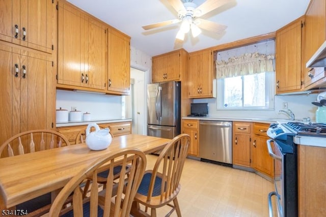 kitchen featuring light floors, light countertops, appliances with stainless steel finishes, brown cabinetry, and a ceiling fan