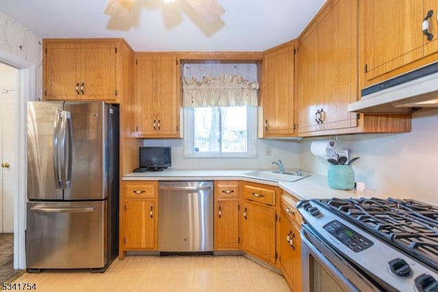 kitchen featuring under cabinet range hood, stainless steel appliances, light countertops, light floors, and brown cabinetry