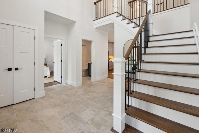 foyer featuring stairs, a towering ceiling, and baseboards