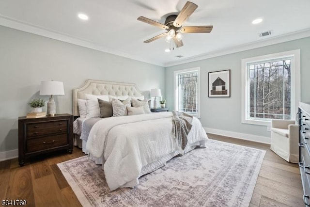 bedroom with ornamental molding, wood finished floors, visible vents, and baseboards