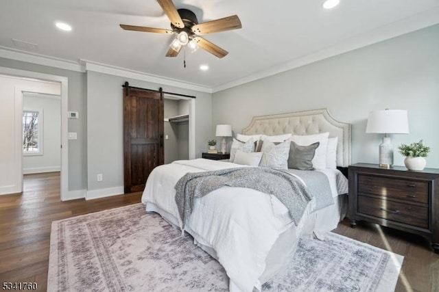 bedroom featuring baseboards, a barn door, ornamental molding, and wood finished floors