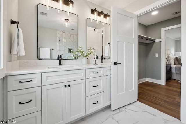 full bath with marble finish floor, a marble finish shower, double vanity, visible vents, and a sink