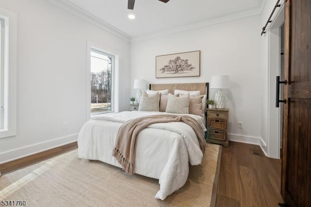 bedroom featuring a barn door, baseboards, ornamental molding, wood finished floors, and recessed lighting