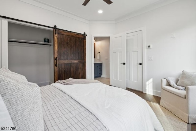 bedroom featuring a barn door, recessed lighting, a ceiling fan, baseboards, and crown molding