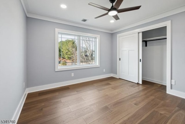 unfurnished bedroom with visible vents, crown molding, baseboards, and wood finished floors