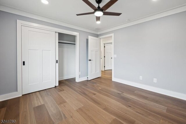 unfurnished bedroom featuring crown molding, recessed lighting, a closet, wood finished floors, and baseboards