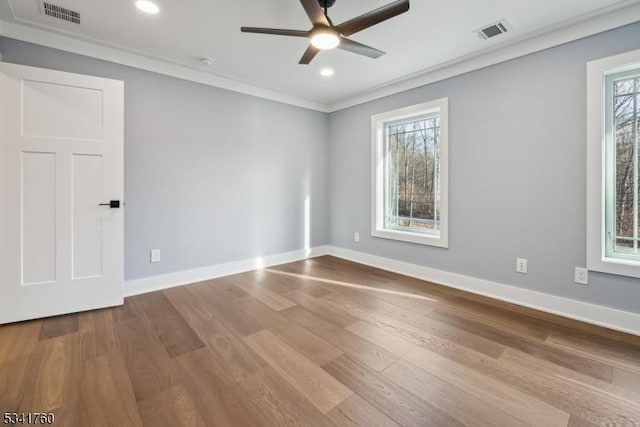 spare room featuring a wealth of natural light, visible vents, and crown molding