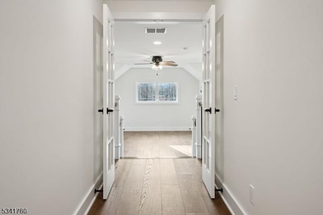 hallway with vaulted ceiling, dark wood-type flooring, visible vents, and baseboards