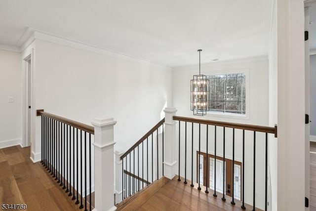 hall featuring crown molding, wood finished floors, an upstairs landing, and a notable chandelier