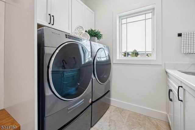 clothes washing area with cabinet space, baseboards, marble finish floor, and washing machine and clothes dryer