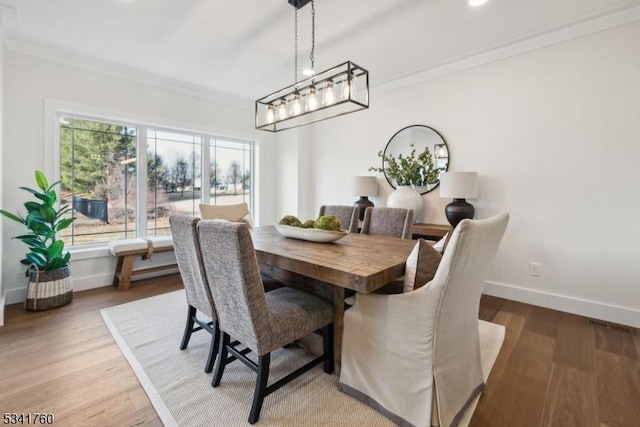 dining room with baseboards, crown molding, and wood finished floors