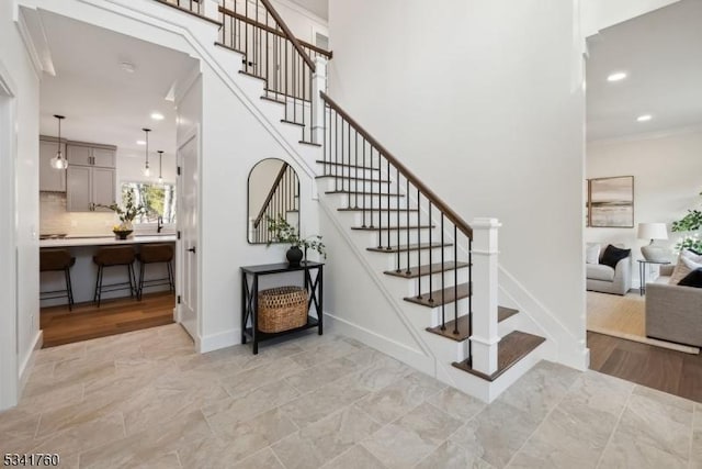 staircase featuring baseboards, ornamental molding, and recessed lighting