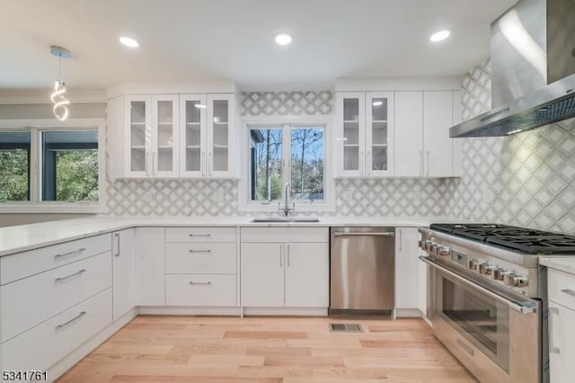 kitchen featuring stainless steel appliances, a healthy amount of sunlight, a sink, and wall chimney exhaust hood