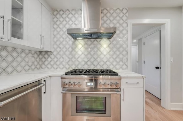 kitchen with stainless steel appliances, decorative backsplash, white cabinetry, and range hood