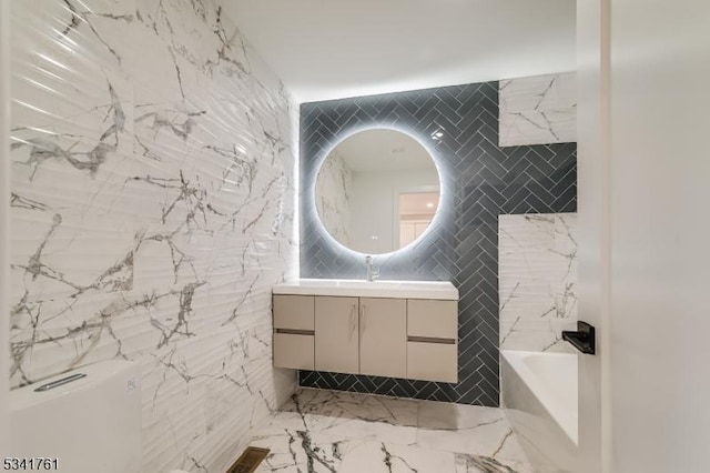 bathroom featuring tile walls, marble finish floor, vanity, stone wall, and a bath