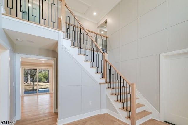 stairs with recessed lighting, a towering ceiling, and a decorative wall